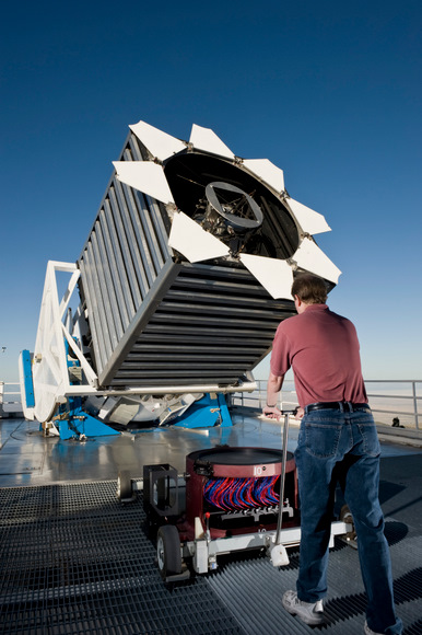 Senior Operations Engineer Dan Long loads the first cartridge of the night into the Sloan Digital Sky Survey telescope. The cartridge holds a “plug-plate” at the top which then holds a thousand optical fibers shown in red and blue. These cartridges are locked into the base of the telescope and are changed many times during a night. Photo credit: D. Long Senior Operations Engineer Dan Long loads the first cartridge of the night into the Sloan Digital Sky Survey telescope. The cartridge holds a “plug-plate” at the top which then holds a thousand optical fibers shown in red and blue. These cartridges are locked into the base of the telescope and are changed many times during a night. Photo credit: D. Long