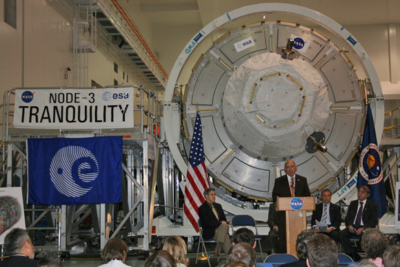 Michael Suffredini, the ISS manager for NASA accepts ownership of the Node 3 Tranquility module from ESA at hand off ceremony inside the Space Station Processing Facility (SSPF) at the Kennedy Space Center on 20 November 2009. Cupola observation module is attached at forward hatch in center and covered with thermal protection blankets. Note robotic arm grapple fixture at lower right. Credit: Ken Kremer