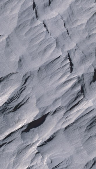 Layers of rock in the upper portion of a tall mound near the center of Gale Crater on Mars exhibit a regular thickness of several meters, unlike the less regular pattern of layers in the lower formation on the same mound. Image credit: NASA/JPL-Caltech/University of Arizona