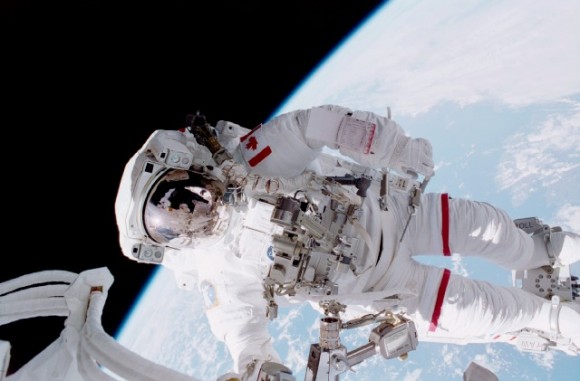 Canadian astronaut Chris Hadfield during one of his two EVAs during the STS-100 mission in 2001. Hadfield is backdropped against the blue and white Earth, and Scott Parazynski, who shared both space walks with Hadfield and who took this photo, appears as a small reflection in Hadfield's helmet visor. Credit: NASA