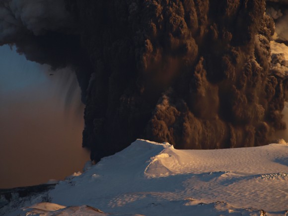 The massive plume of Eyjafjallajokull volcano dwarfs a helicopter flying nearby (upper left). Image courtesy of and copyright Snaevarr Gudmundsson.