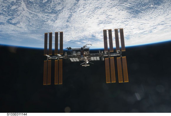 Backdropped against the blackness of spaec and clouds over Earth, the International Space Station is seen from Discovery as the shuttle departed from the station. Credit: NASA