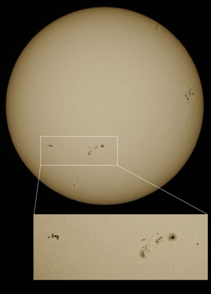 The International Space Station and a just-undocked space shuttle Discovery transit the surface of the Sun, appearing near an active spot region, 1166. Credit: Catalin Fus. Used by permssion.
