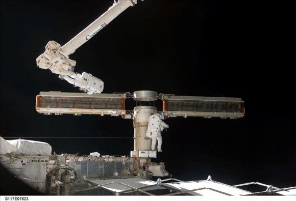 June 15, 2007 – Shuttle Mission STS-117 continued assembly operations that featured more work on the Station’s solar arrays. In this image, NASA astronaut Jim Reilly, attached to Canadarm2, and NASA colleague John “Danny” Olivas, are folding up an older solar panel so that it can be stowed and moved to another location on a future shuttle mission. Credit: NASA