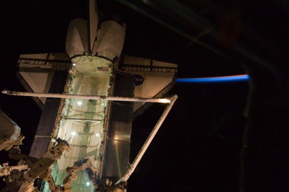 Shuttle Endeavour docked to the ISS, backdropped by a thinly lit part of Earth's atmosphere and the blackness of orbital nighttime in space. Credit: NASA