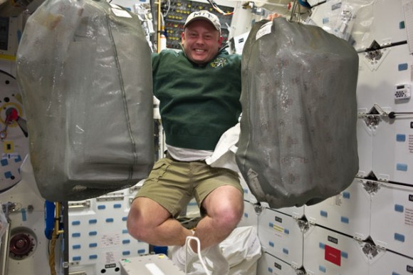 NASA astronaut Michael Fincke, STS-134 mission specialist, appears delighted that, because of the weightlessness of space, he can renew doing chores which he can't do on Earth, like lifting heavy bags and floating freely at the same time. Credit: NASA