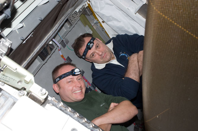 NASA astronauts Michael Fincke (left), STS-134 mission specialist; and Ron Garan, Expedition 28 flight engineer pose with their headlights, worn so they can see while working behind a rack on the International Space Station. Credit: NASA