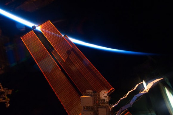 One of the solar array wings on the ISS is backlit by a thin line of Earth's atmosphere. Credit: NASA