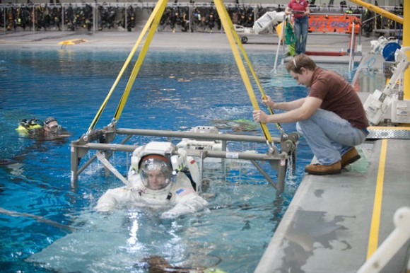 Here’s how astronauts train for their EVAs, in the Neutral Buoyancy Laboratory (NBL) near NASA's Johnson Space Center. Here astronauts Rex Walheim and Sandy Magnus (mostly obscured), are raised from the waters of the N as a spacewalk training session comes to a close. Divers were in the water to assist Magnus and Walheim in their rehearsal. Credit: NASA