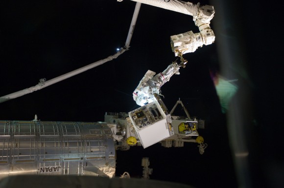 No, this isn't a picture of an astronaut carrying a freezer outside the space station. With his feet secured on a restraint on the space station remote manipulator system's robotic arm Canadarm2, Mike Fossum holds the Robotics Refueling Mission payload, an experiment which will test in-flight refueling with the DEXTRE robot. Fossum and Ron Garan installed the experiment during the July 12 EVA. Credit: NASA