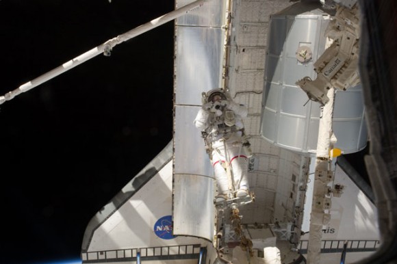 Space shuttle Atlantis makes a cameo in this image as Mike Fossum takes a picture during the spacewalk while on a foot restraint on the Canadarm 2. Credit: NASA