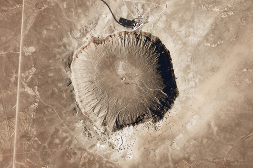 Barringer Crater, also known as Meteor Crater, in Arizona. This crater was formed around 50,000 years ago by the impact of a nickel-iron meteorite. Near the top of the image, the visitors center, complete with tour buses on the parking lot, provides a sense of scale. Credit: National Map Seamless Viewer/US Geological Service