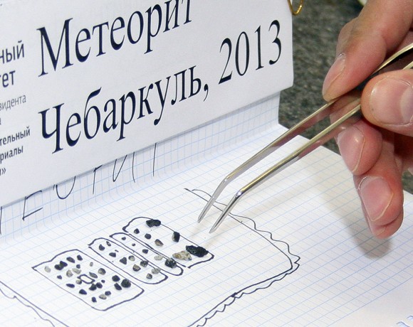 Some of the 53 meteorites found around Chebarkul Lake. Many are coated with a thin crust of melted and blackened rock heating by the atmosphere. The sign reads: Meteorite Chebarkul. Credit: AP / The Urals Federal University Press Service, Alexander Khlopotov