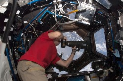 Canadian Space Agency astronaut Chris Hadfield uses a camera to photograph the topography of a point on Earth from a window in the Cupola of the International Space Station. Credit: NASA