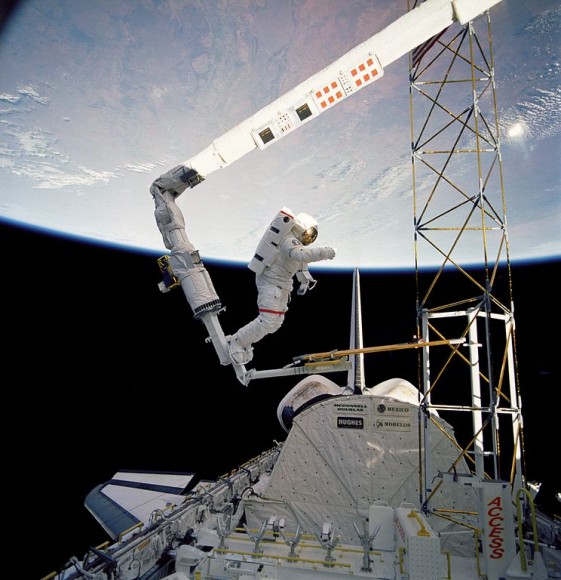 Jerry Ross on the end of the space shuttle's RMS during STS-61B in 1985, demonstrating the feasibility of assembling structures in space. Credit: NASA.