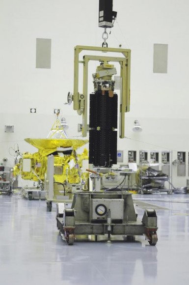 The plutonium-fueled RTG (foreground) awaiting installation on New Horizons (background). (Credit: NASA).