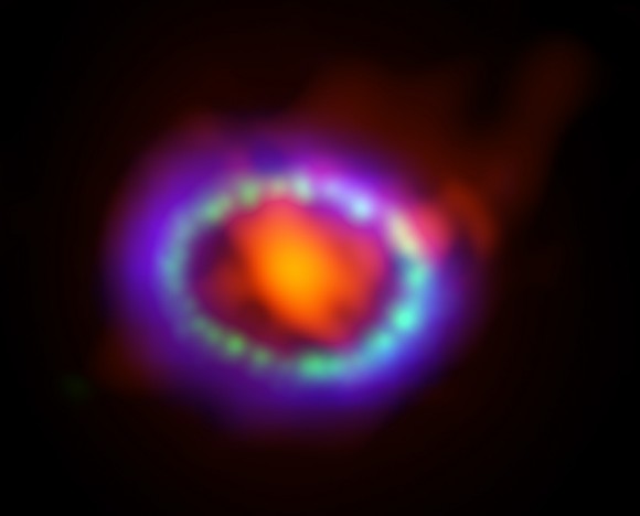 Composite image of supernova 1987A. ALMA data (in red) shows newly formed dust in the center of the remnant. HST (in green) and Chandra (in blue) show the expanding shockwave. Credit: R. Indebetouw et. al, A. Angelich (NRAO/AUI/NSF); NASA/STScI/CfA/R. Kirshner; NASA/CXC/SAO/PSU/D. Burrows et al.