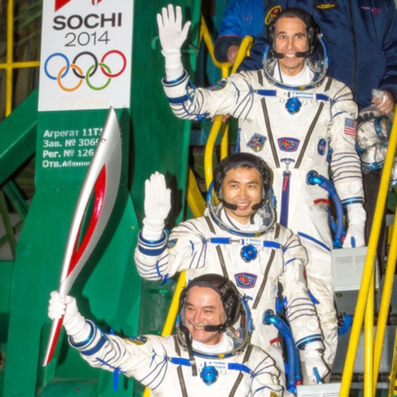 Expedition 38 Soyuz Commander Mikhail Tyurin, holding the Olympic torch, and Flight Engineers Koichi Wakata and Rick Mastracchio wave farewell prior to boarding the Soyuz TMA-11M rocket for launch. (NASA/Bill Ingalls)