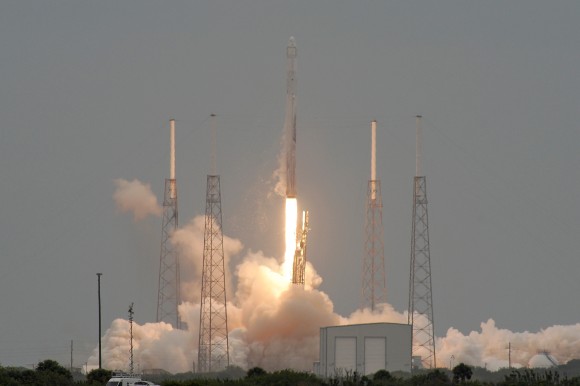 'Threading the needle', the Falcon 9/Dragon vehicle passes through the catenary lightning wires as it roars from the pad on the CRS-3 mission. Credit: nasatech.net