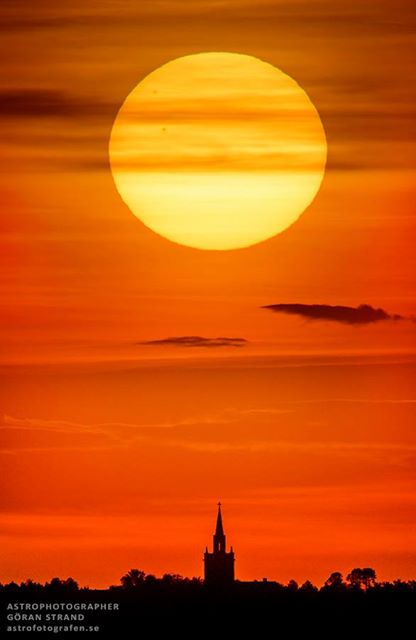 The setting Sun as it passed over the church of a small village called Ås. You can clearly see two sunspots visible on the Sun (#2079 and #2077), both about the size of one Earth diameter. Credit and copyright: Göran Strand.