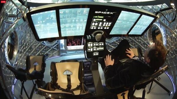 Elon Musk seated inside Dragon V2 explaining consoles at unveiling on May 29, 2014. Credit: SpaceX