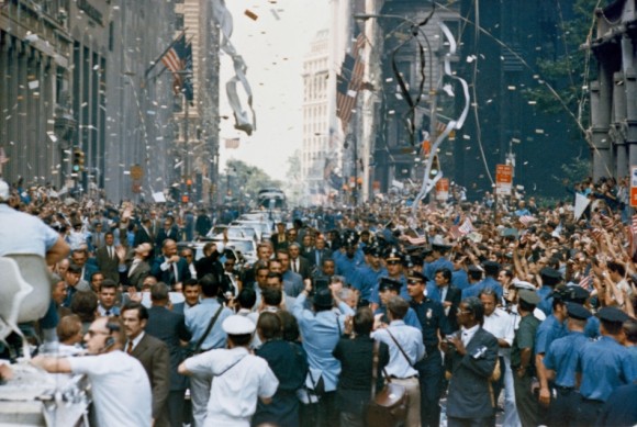Apollo 11 Welcome. New York City welcomes the Apollo 11 crew in a ticker tape parade down Broadway and Park Avenue. Pictured in the lead car, from the right, are astronauts Neil A. Armstrong, Buzz Aldrin and Michael Collins. The three astronauts teamed for the first manned lunar landing, on July 20, 1969. Credit: NASA