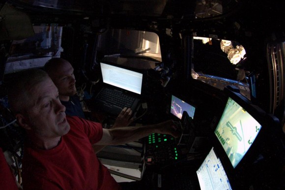In this photo posted to Twitter by Flight Engineer Alexander Gerst, he and Commander Steve Swanson (foreground) use the robotics workstation in the International Space Station's cupola. Image Credit: NASA