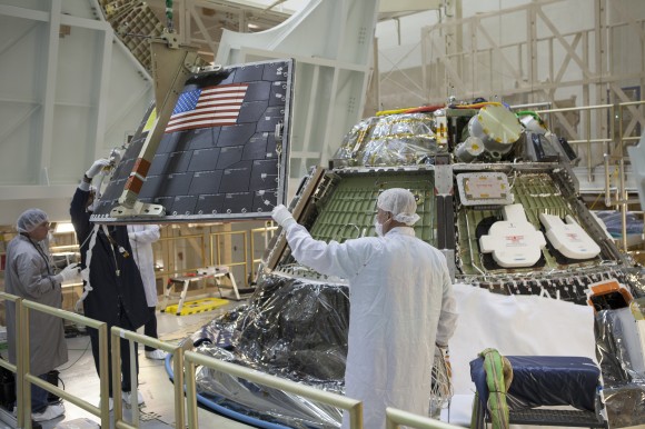 Inside the Operations and Checkout Building high bay at the Kennedy Space Center, Fl, technicians on work platform monitor progress as crane lowers the middle back shell tile panel for installation on the Orion crew module. Credit: NASA/Dimitri Gerondidakis